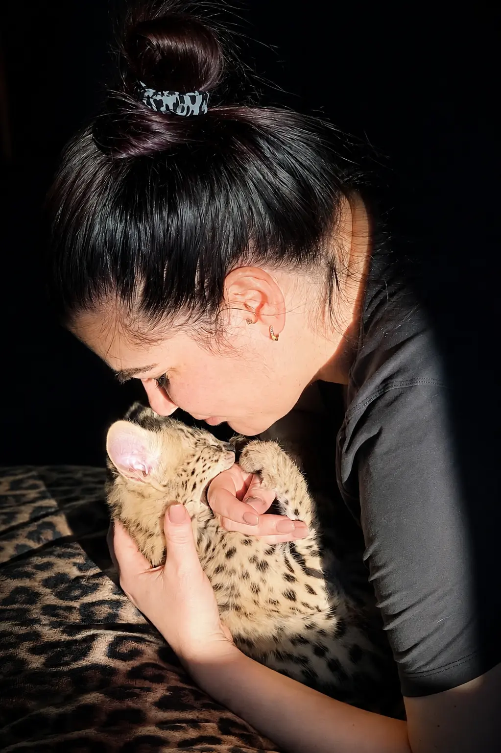 Woman cuddling a spotted Devon Rex kitten